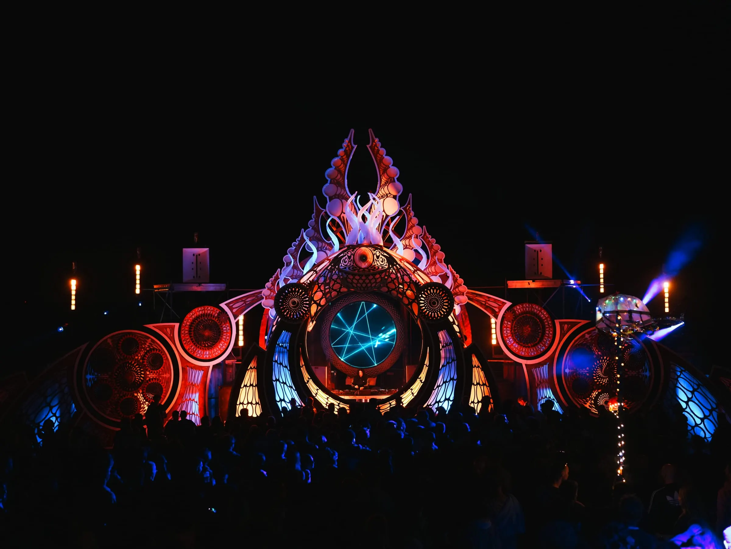 Feel Festival · Beach Stage 2024 – The 2024 beach stage – tentacles reaching up into the night, crowned by fire, framing a glowing eye of laser light.